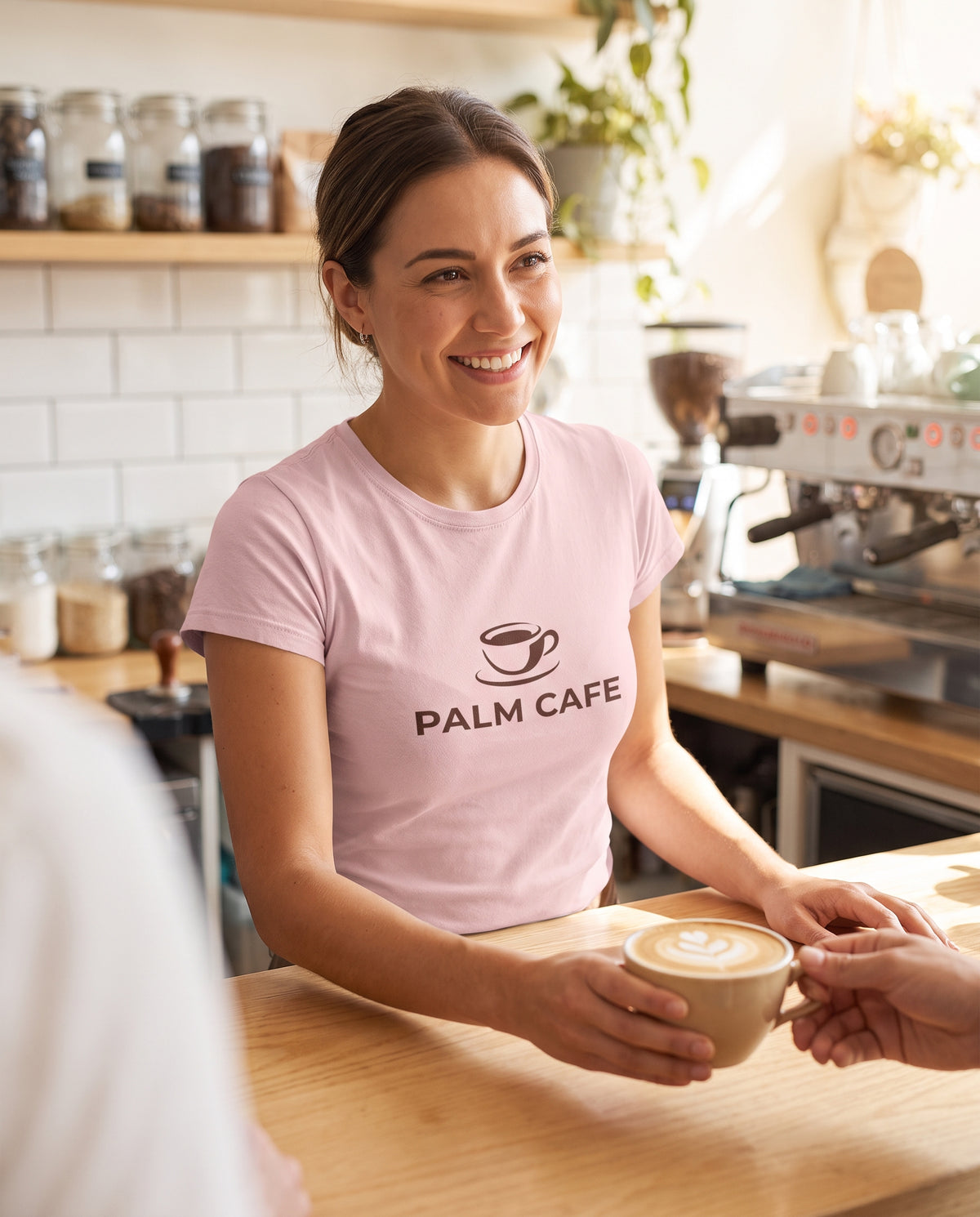 Barista wearing a custom pink logo t-shirt serving a latte
